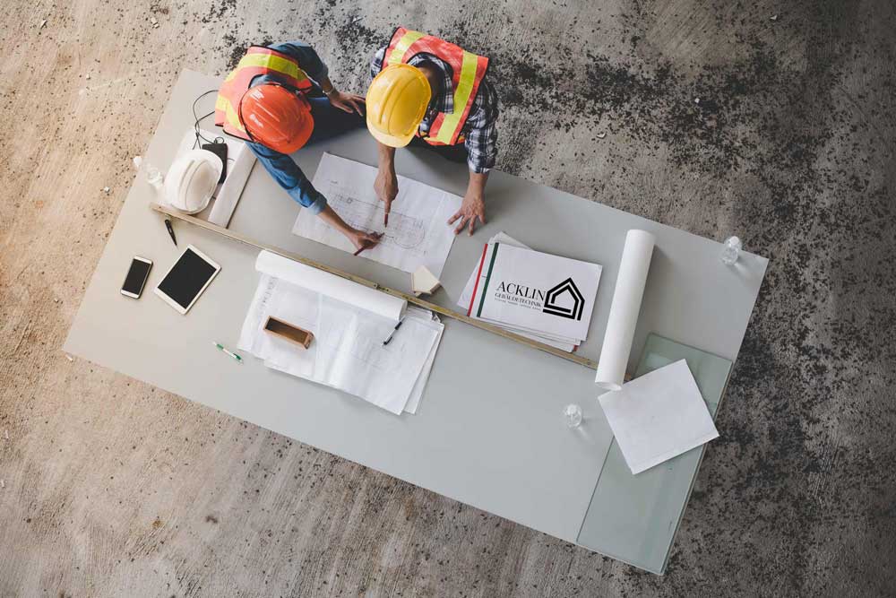 Zwei Personen arbeiten an einem Tisch an Bauplänen.