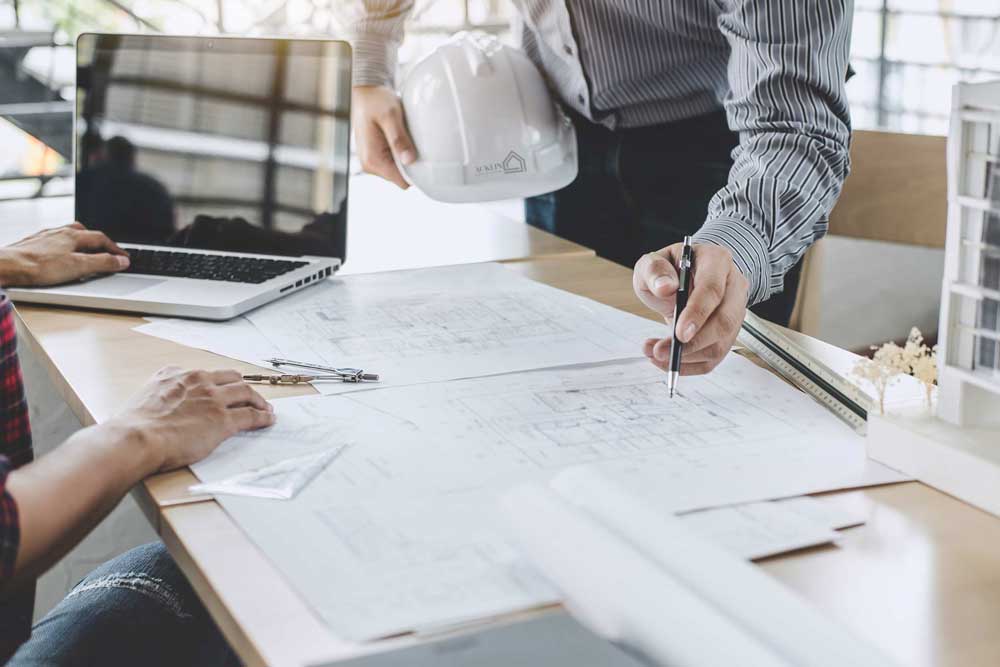 Architektenteam arbeitet gemeinsam an Bauplänen in einem modernen Büro.